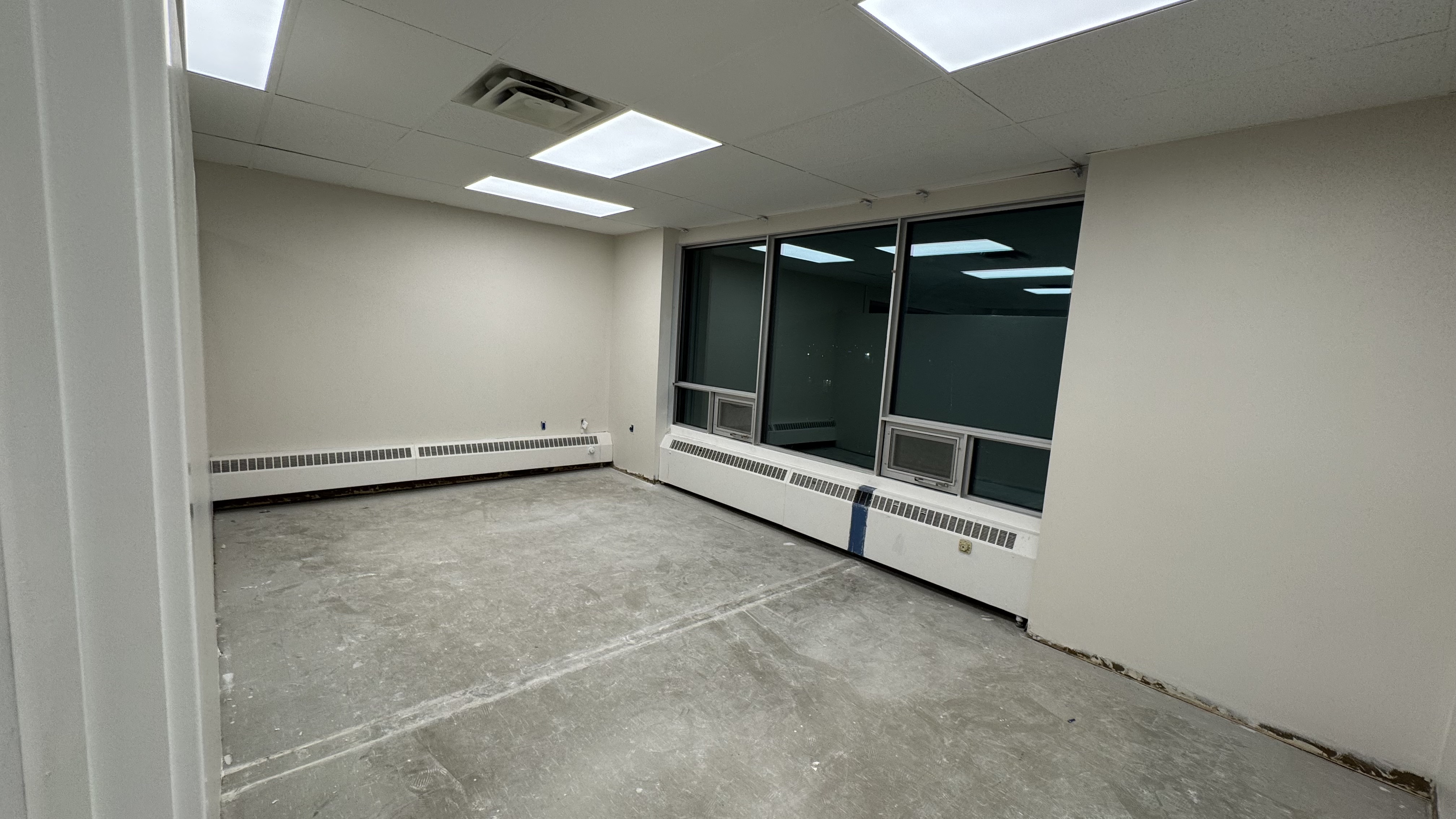 Commercial fit-out: baseboard heaters masked, walls repaired and rolled, room by room — YZ Painting & Finishing, Greater Vancouver